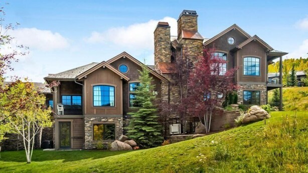 A two-story house with a stone facade, large windows, and a sloped roof. - Premier Ski in, Ski-out 1 Bedroom Condo With Spectacular Views, Heated Outdoor Pool and Hot Tub, Short Walk to Village (Snowmass Village)