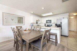 A modern kitchen with white cabinetry, a dining table with chairs, and a built-in microwave. - Las Palmas Resort #1613 | All-Inclusive Amenities (Saint George)