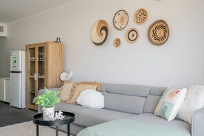 A living room with a grey sofa, a wooden cabinet, and decorative woven wall art.