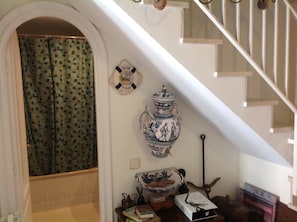 A staircase with a white railing, a decorative ceramic urn, and a welcome sign on the wall.