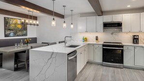 A modern kitchen with a marble island, stainless steel appliances, and pendant lighting. - Warm and Cozy 3 Bedroom Ski In, Ski Out Condo in Snowmass Base Village (Snowmass Village)