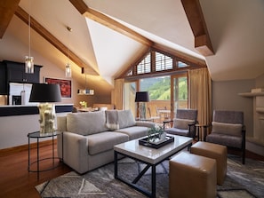 Ein geräumiges Loft mit hoher Decke, einer gemütlichen Sitzecke mit Sofa und Sesseln, einem Esstisch und einer Küche mit modernen Geräten.