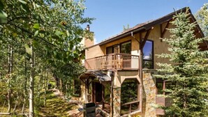 A rustic cabin with a stone exterior, a balcony, and a wooden deck.