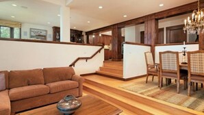 Ein geräumiges Wohnzimmer mit braunem Sofa, einem Holztisch und einem Essbereich mit Holzstühlen und einer Kronleuchter.