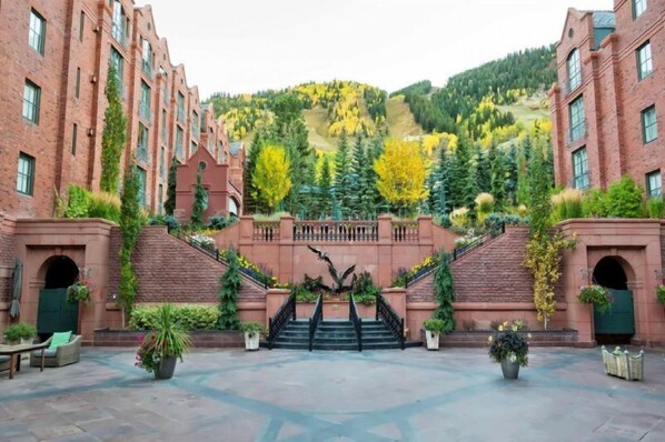 A courtyard with a central staircase, brick buildings, and a hillside with trees. - Aspen St. Regis Luxury 3 Bedroom Residence - 5-star Resort in World Class Destination (Aspen)