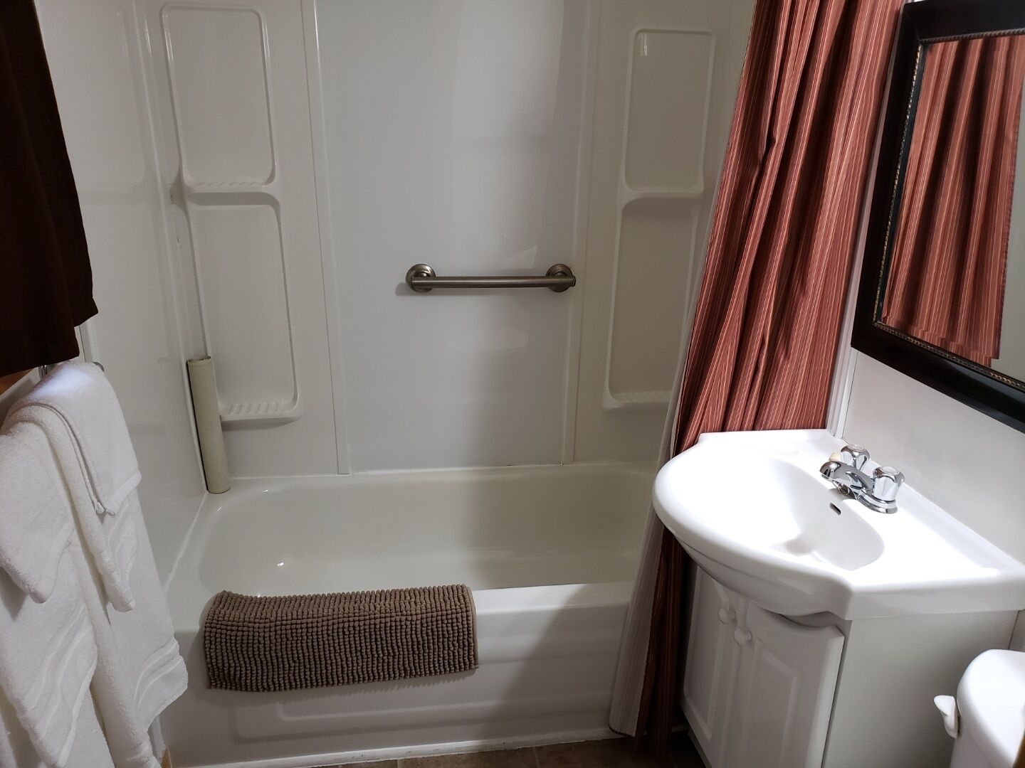 Un baño con una bañera, un lavabo blanco y un espejo.