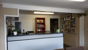 Een receptiebalie met een boekenkast, een potplant en een fotopresentatie aan de muur.