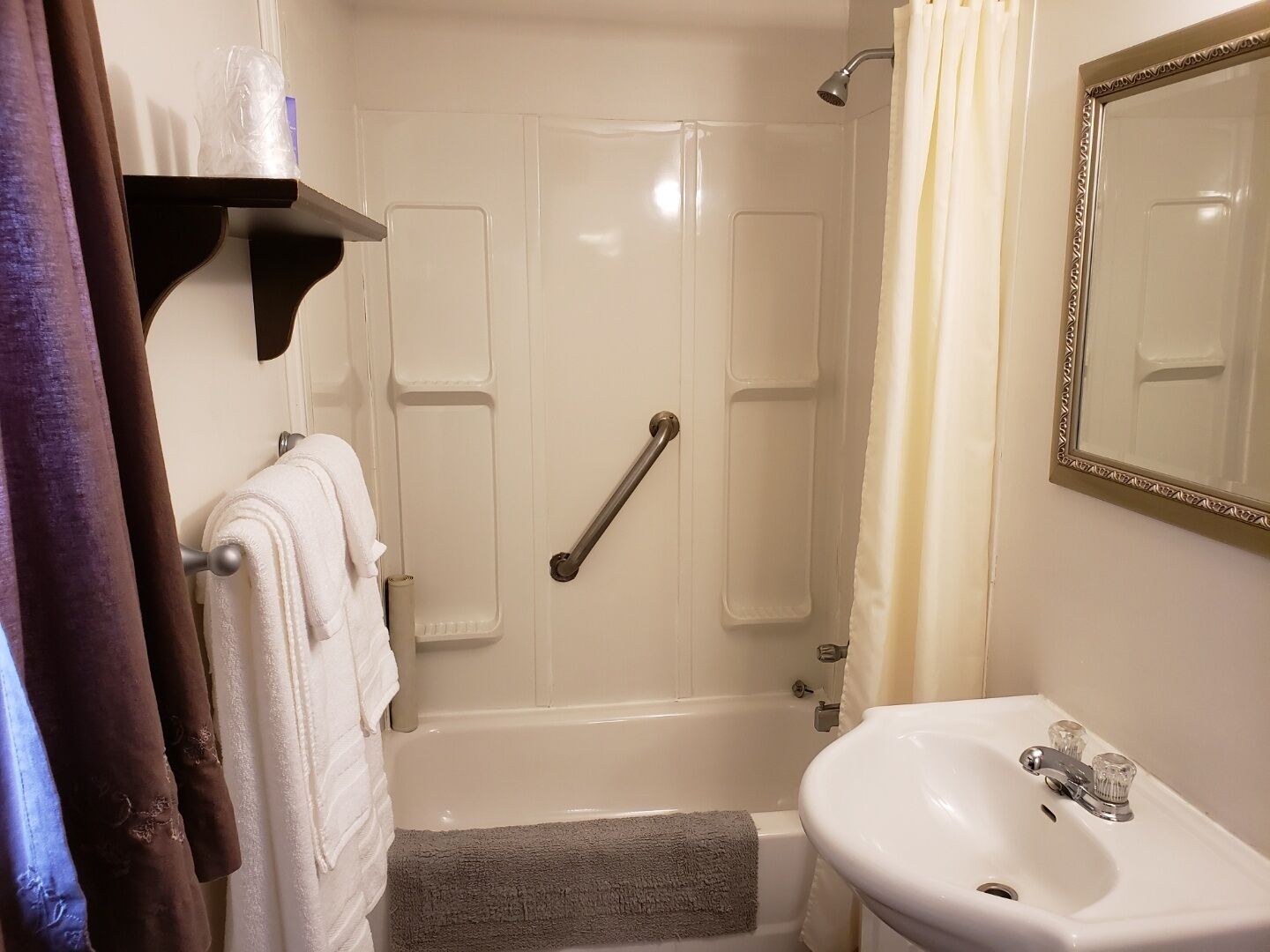 A bathroom with a bathtub, a shower, a sink, and a mirror.