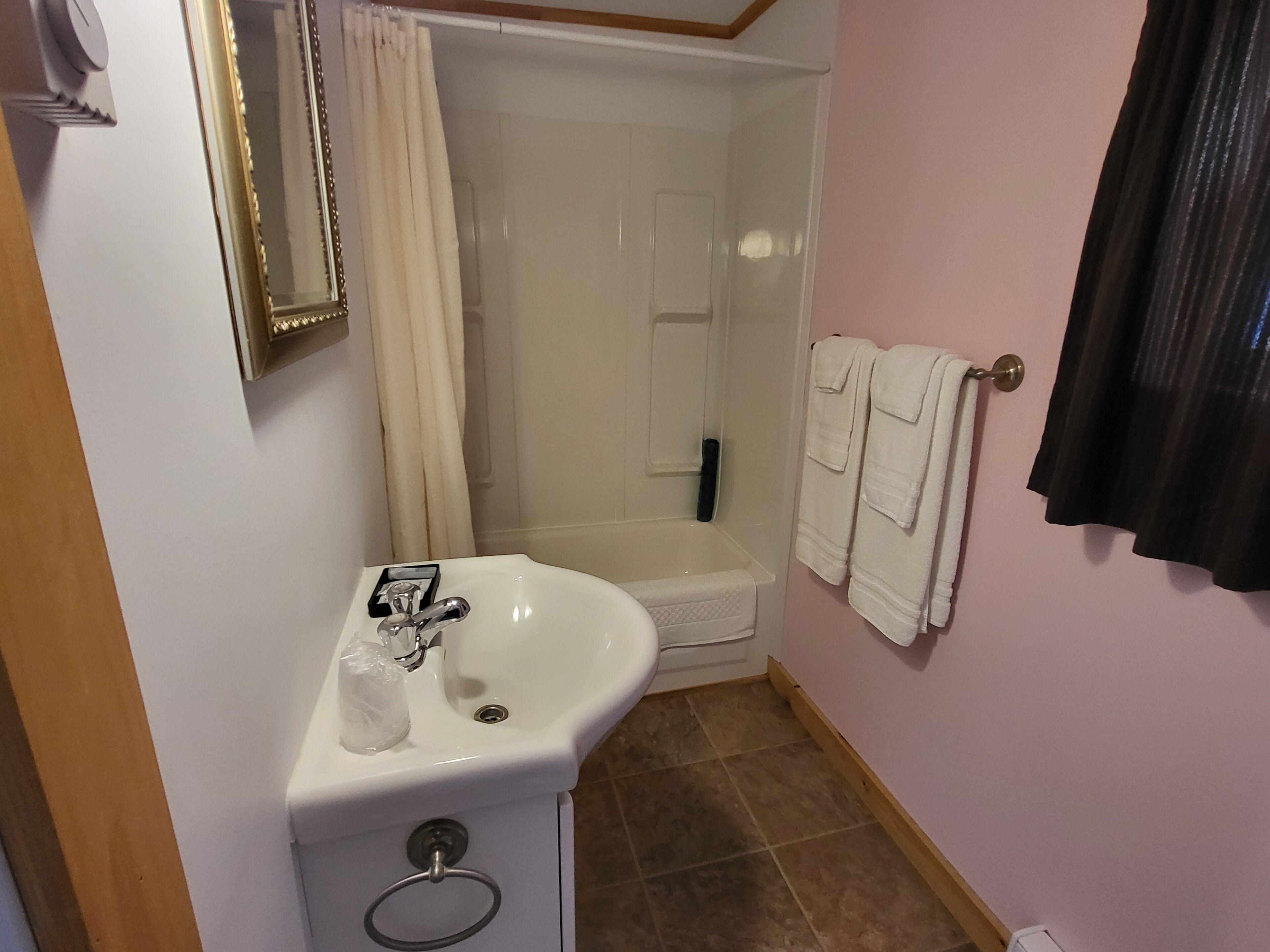 Een badkamer met een wastafel, spiegel, douche en handdoeken.