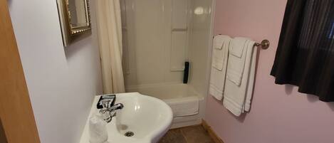 Un baño con lavamanos, espejo, ducha y toallas.