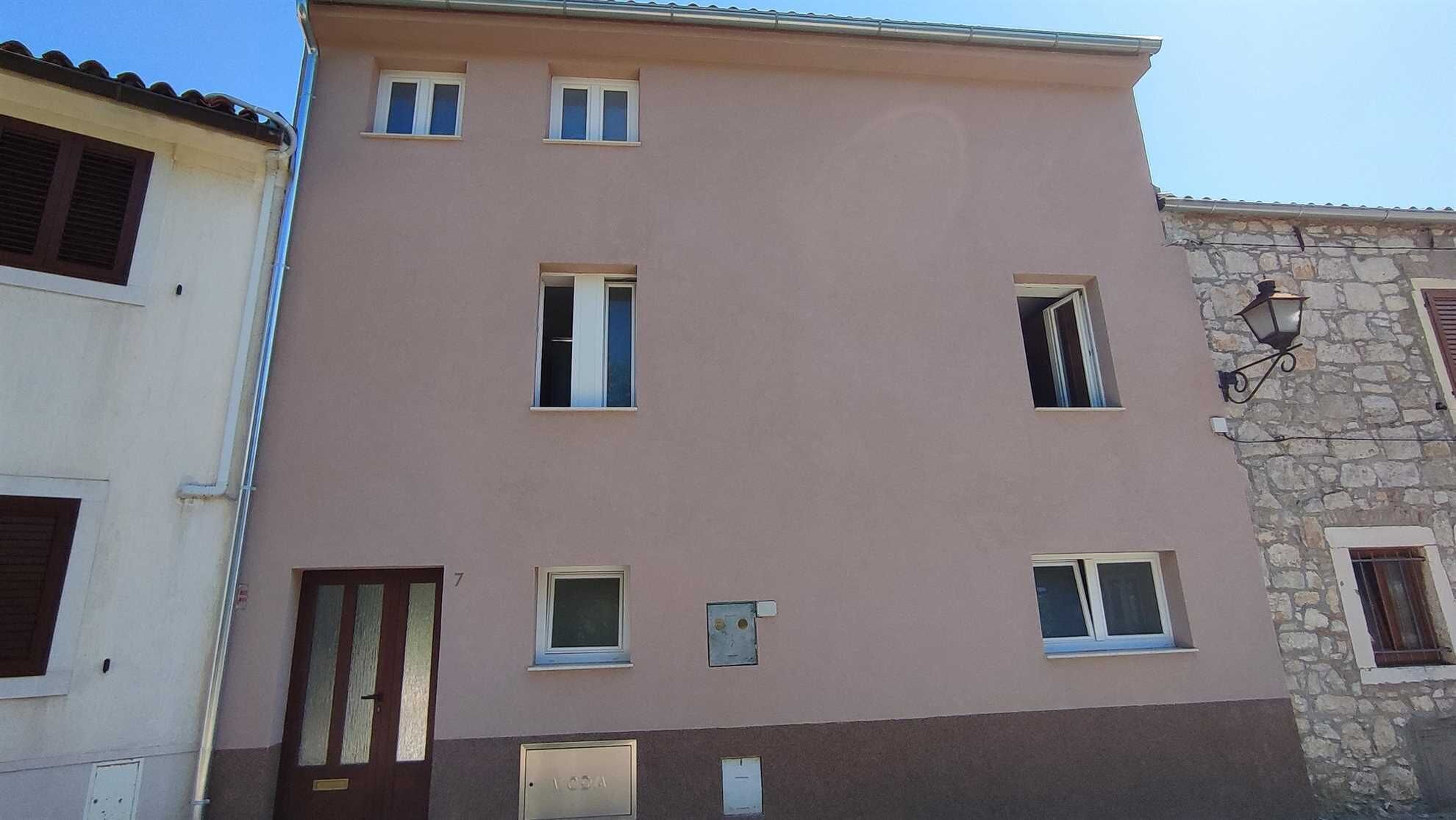 A multi-story building with a flat facade, several windows, and a door.