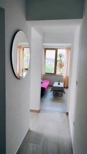 Un pasillo estrecho con una cama, una mesa y una ventana con cortinas.