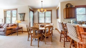 A spacious living room with a dining area, large windows, and a kitchen area. - Red Hawk Townhomes 2 Bedroom Rental in River Run Village (Keystone)