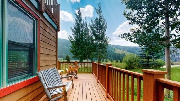 A wooden deck with two chairs and a table, overlooking a mountainous landscape. - Red Hawk Townhomes 2 Bedroom Rental in River Run Village (Keystone)