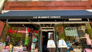 Una fachada comercial con un letrero que dice "112 MARKET STREET" y un escaparate con varios artículos.