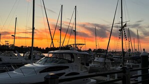 Un puerto deportivo con varias embarcaciones amarradas, y un cielo con colores de atardecer al fondo.