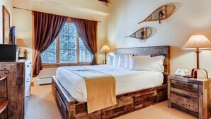 A bedroom with a wooden bed, a desk, and a window with curtains. - Beautiful 2 Bedroom Mountain Condo in River Run Village With Hot Tub Access and Walking Distance to the Gondola (Keystone)