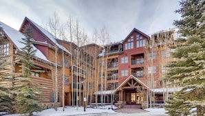 A multi-story lodge with a rustic log cabin exterior, multiple balconies, and a central entrance with a porch. - Beautiful 2 Bedroom Mountain Condo in River Run Village With Hot Tub Access and Walking Distance to the Gondola (Keystone)