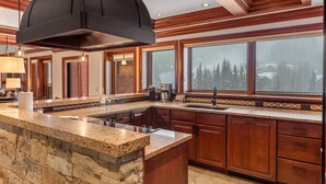 A modern kitchen with a large island, granite countertops, and wooden cabinetry. - Exclusive 4 Bedroom Ski in, Ski out Vacation Rental With Hot Tubs and Heated Outdoor Pool in Lionshead Village (Vail)