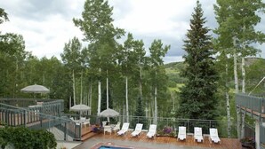 Un espace piscine comprenant deux piscines, des chaises longues et des parasols.