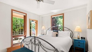 Un dormitorio con cama, mesitas de noche y ventana con vistas a zonas verdes.