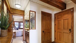 A hallway with wooden doors, a potted plant, and a view into another room. - Snowmass Village 2 Bedroom Platinum-rated Ski In, Ski Out Condo (Snowmass Village)