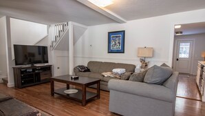 A living room with a television, sofa, coffee table, and a staircase.