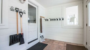 A hallway with white wooden walls, a black doormat, and a door with a glass panel.