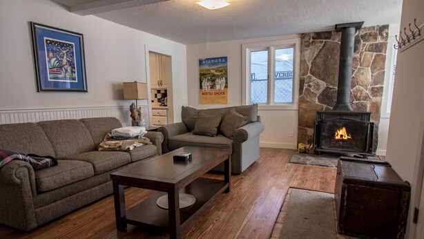A cozy living room with a stone fireplace, a sofa, a coffee table, and a rug.