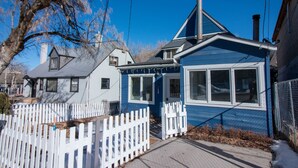 A residential house with a white picket fence, a blue exterior, and a visible chimney.