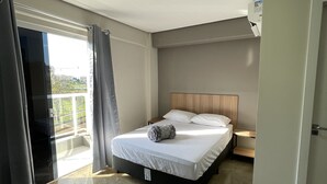 Habitación de hotel moderna con una cama grande, vistas al exterior y un ventilador de techo.