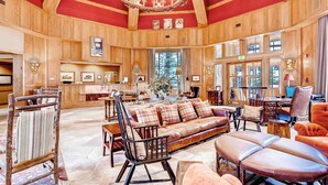 A spacious room with a large wooden ceiling, a sofa set, and a dining area.