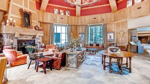 A spacious living room with a fireplace, wooden walls, and a chandelier.