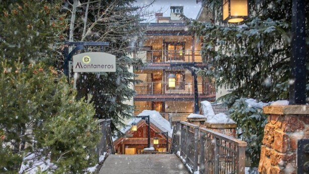 A hotel entrance with a sign reading "Montaneros," a wooden staircase, and a snow-covered environment. - 1 Bedroom Boutique Resort Condo With Hot Tub Access and Within Walking Distance to the Eagle Bahn Gondola (Vail)