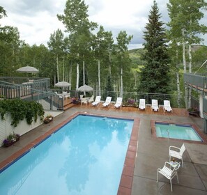 Un espace piscine comprenant deux piscines, des chaises longues et des parasols.