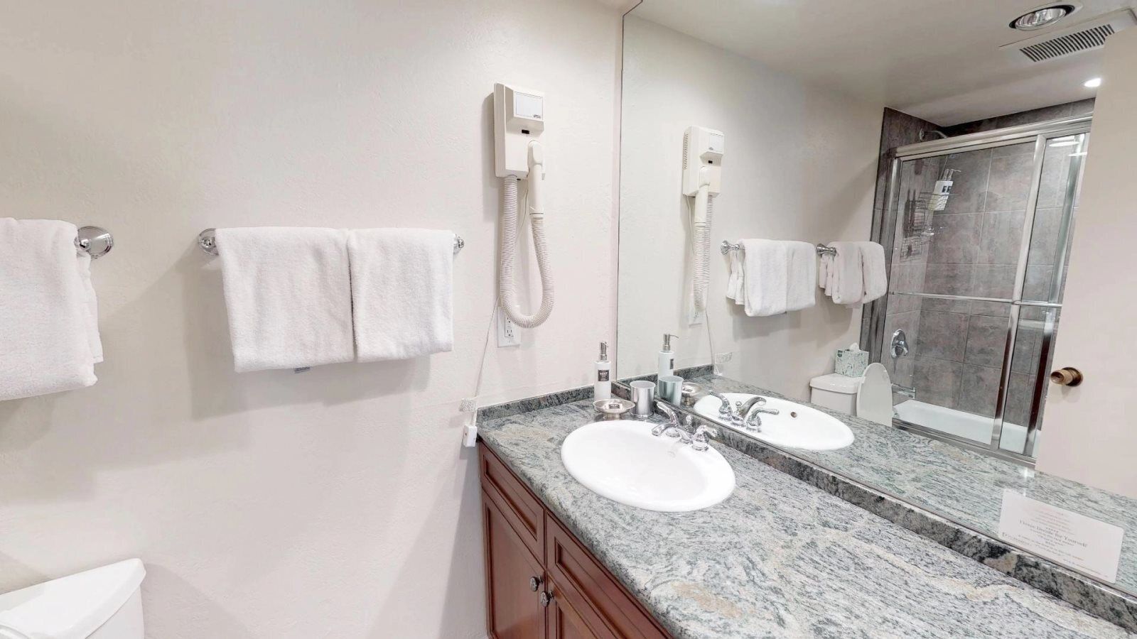 A modern bathroom with two sinks, a large mirror, and a shower enclosure.