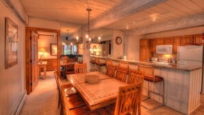 A cozy kitchen with wooden cabinets, a dining table, and a chandelier. - Comfortable and Convenient Ski In, Ski Out 4 Bedroom Condo in Snowmass Village (Snowmass Village)