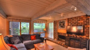 A cozy living room with a sectional sofa, a coffee table, a fireplace, and a TV mounted on the wall. - Comfortable and Convenient Ski In, Ski Out 4 Bedroom Condo in Snowmass Village (Snowmass Village)