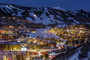 Une ville recouverte de neige, avec des bâtiments illuminés et des rues sinueuses.