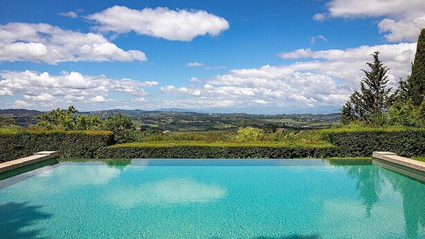 Une piscine d’un bleu éclatant, avec vue sur des collines lointaines et un ciel dégagé.