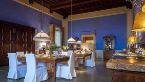 Un espace repas avec des tables et des chaises en bois, des lustres et un grand miroir.