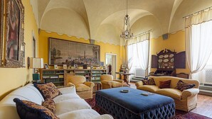 Un salon spacieux comprenant un grand fauteuil, un canapé, une table basse et une bibliothèque remplie de livres.