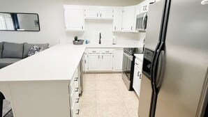 A modern kitchen with white cabinetry, a stainless steel refrigerator, and a central island.
