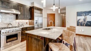 A modern kitchen with a central island, stainless steel appliances, and wooden cabinetry.
