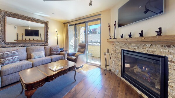 A living room with a fireplace, a sofa, a coffee table, and a television mounted on the wall.