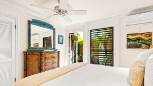 A bedroom with a large bed, a wooden dresser, a ceiling fan, a window with blinds, and a painting on the wall. - Poipu Beach Kauai Honeymoon: View Sea Turtles From Your Oceanfront Deck-AC (Koloa)