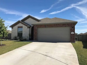 Stunning single-story home with a brick and stone exterior, complete with a garage and beautifully manicured lawn.