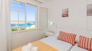 A bedroom with a bed, a nightstand, a lamp, and a view of the sea. - Lovely 2-bedrooms condo just 300 mts from beach (Arenal d`en Castell)