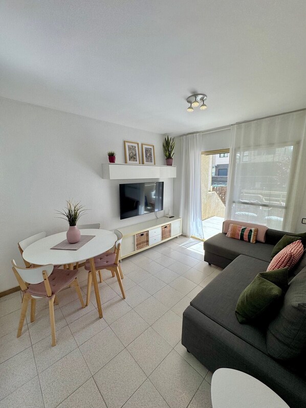 A living room with a TV, sofa, and dining table.