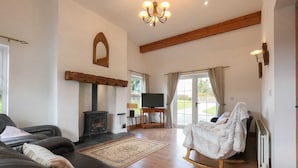 A cozy living room with a fireplace, a television, and a rocking chair. - The Heights & Hollows Farmhouse (Downpatrick)
